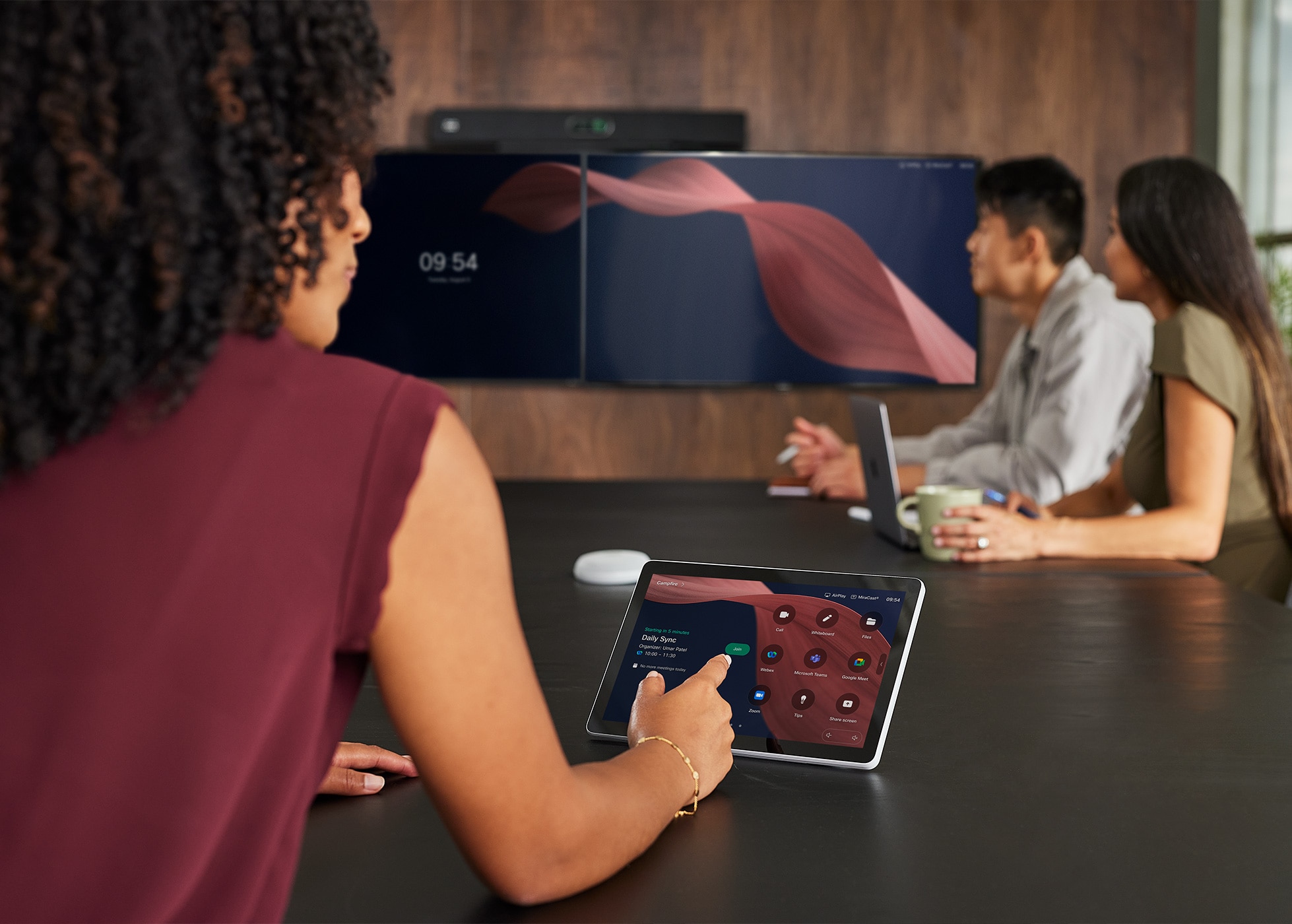 Person taps Webex Desk Mini’s touch screen to join Zoom meeting. Screen shows apps like Google Meet, Microsoft Teams, and Zoom